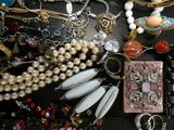 many different necklaces and bracelets laid out on a table