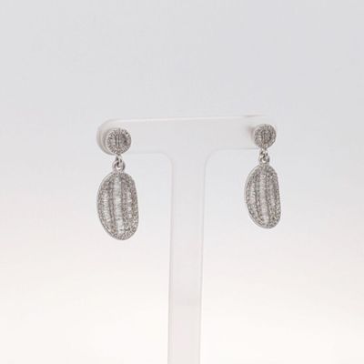 une paire de boucles d'oreilles en diamant posée sur un présentoir, sur fond blanc