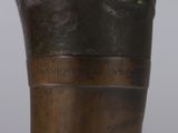 a close up of a bronze vase with a flower on it