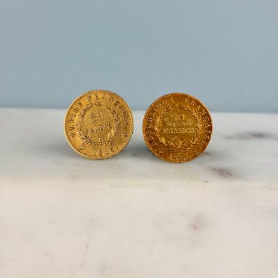 deux pièces d'or posées l'une à côté de l'autre sur une surface en marbre