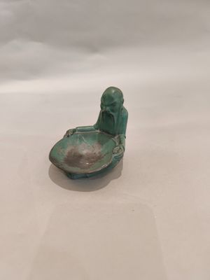 une petite figurine représentant un homme assis dans un bateau