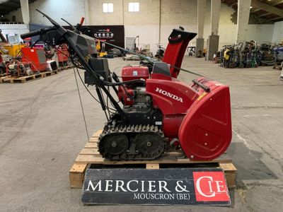 une déneigeuse rouge posée sur une palette dans un entrepôt