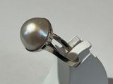 bague en argent ornée d'une perle posée sur un fond blanc