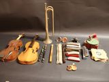 un violon, une trompette, un étui à violon et d'autres instruments de musique disposés sur une table