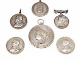six silver coin pendants of various sizes and shapes on a white background