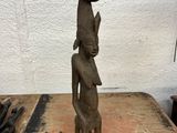 statue of a woman holding a pot on her head on a wooden table