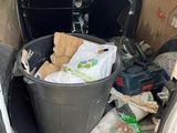 a trash can in the back of a van filled with garbage