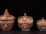 trois types différents de vases avec couvercle, posés sur un fond noir