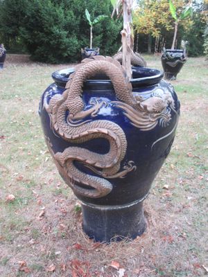 un vase bleu orné d'un dragon, posé dans l'herbe