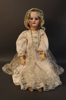 an old fashioned doll with a white dress and hat on a black background