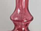 purple glass vase on a white table with a gray background