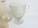 trois vases en verre et une bouteille en verre posés sur une table