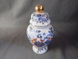 a blue and white vase with a gold lid