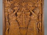a carved wooden plaque depicting a group of women with baskets of fruit