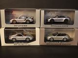 three silver porsche models in boxes on a black surface