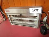 a metal heater sitting on the floor next to a bag