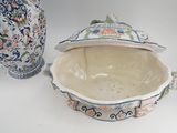 a bowl with a lid sitting next to a vase on a table
