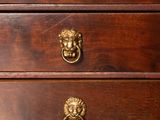 a wooden chest of drawers with a lion head on it