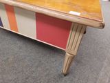 une table en bois avec un plateau et des pieds rayés de couleurs vives
