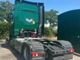 a green semi truck parked next to a green building
