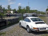 a white car parked on the side of the road next to a canal