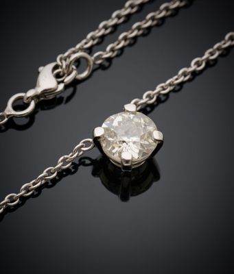 un collier de diamants suspendu à une chaîne, posé sur une surface noire