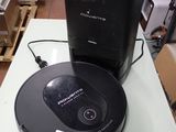 un robot noir posé sur une table, à côté d'une boîte noire