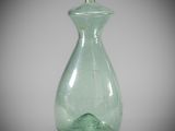 a green glass bottle with a silver top on a table