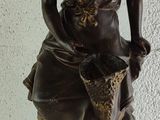 bronze statue of a woman holding a basket of fruit on a pedestal