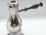 an antique silver coffee pot with a wooden handle on a white surface