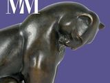 une statue en bronze représentant un chat assis sur une table