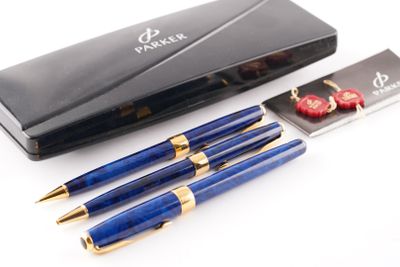 deux stylos et un stylo dans un étui, posés sur une surface blanche