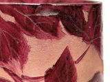a close up of a vase with red leaves on it