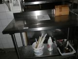 une cuisine équipée d'un évier et d'un plan de travail sur lequel sont posés de nombreux ustensiles