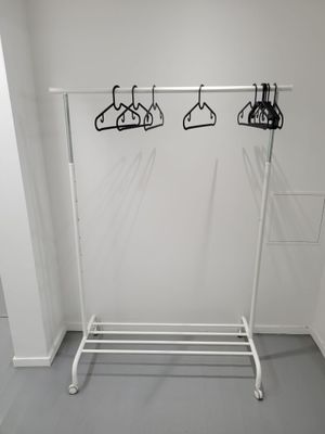a white rack with clothes hanging on it in a room