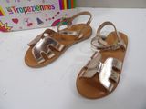 the children ' s gold sandals are on a white table next to a box of toys
