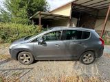La voiture est garée devant un garage, sur la terre battue.