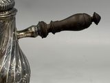 silver plated tea pot with a wooden handle and a wooden handle on a stand
