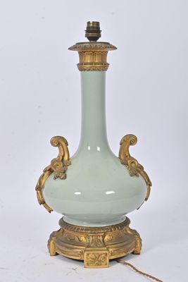 a green and gold vase on a stand with a chain around it