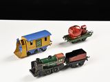 trois petits trains miniatures posés sur une surface blanche, sur fond noir