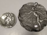 a silver plate with a picture of a woman on it next to a silver coin