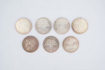 six different coins are arranged in a row on a white surface