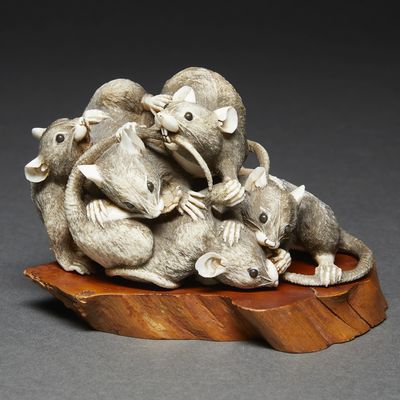 a statue of a group of mice sitting on a piece of wood