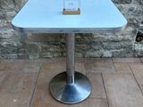 a white table with a glass top on a brick floor