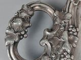 a silver vase with flowers on it sitting on a table