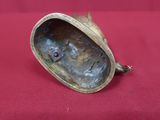 une figurine antique en bronze représentant le visage d'une femme, posée sur un tissu rouge
