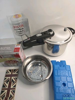 une casserole en argent avec un couvercle, posée sur un plan de travail à côté d'autres objets