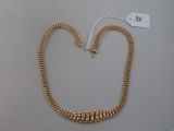 a close up of a gold necklace on a white surface