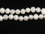 un gros plan sur un collier de perles blanches sur fond noir