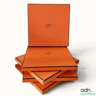 trois boîtes orange sont empilées les unes sur les autres sur une surface blanche